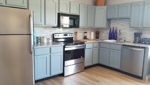A modern kitchen with light blue cabinets, stainless steel appliances, and a wooden floor. - Amazing Renovated Historic Loft on Main Street (Saint Charles)