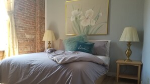 A bedroom with a bed, pillows, a lamp, and a painting on the wall. - Amazing Renovated Historic Loft on Main Street (Saint Charles)