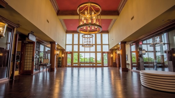 A spacious lobby with a high ceiling, large windows, and a central chandelier.