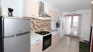 A modern kitchen with a stainless steel refrigerator, a gas stove, and a built-in oven. There is a tiled backsplash and a window with curtains. - Apartments Rubil (Bale)