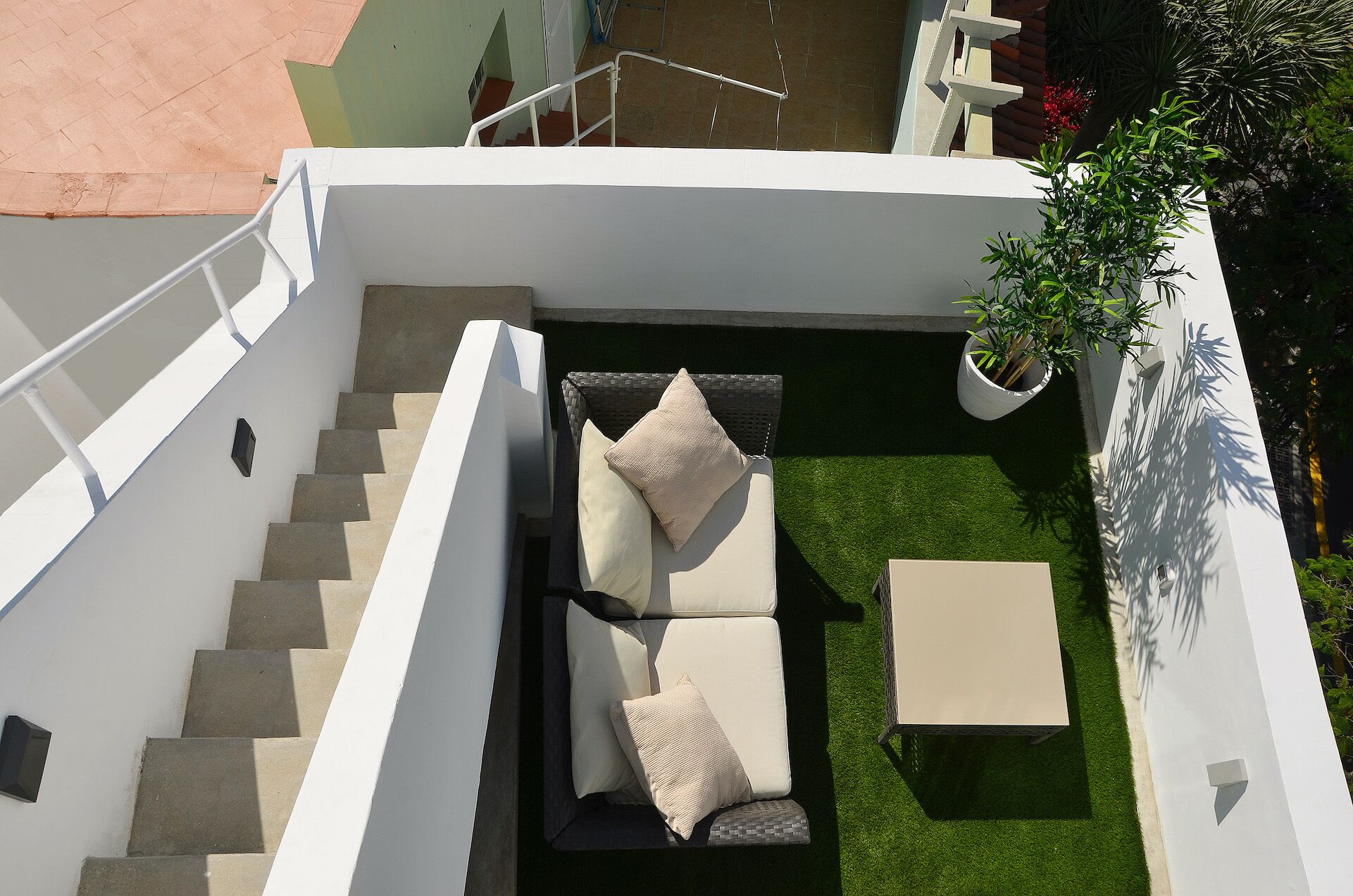 A modern outdoor living area with a sofa set, a small table, and a staircase leading to an upper level.