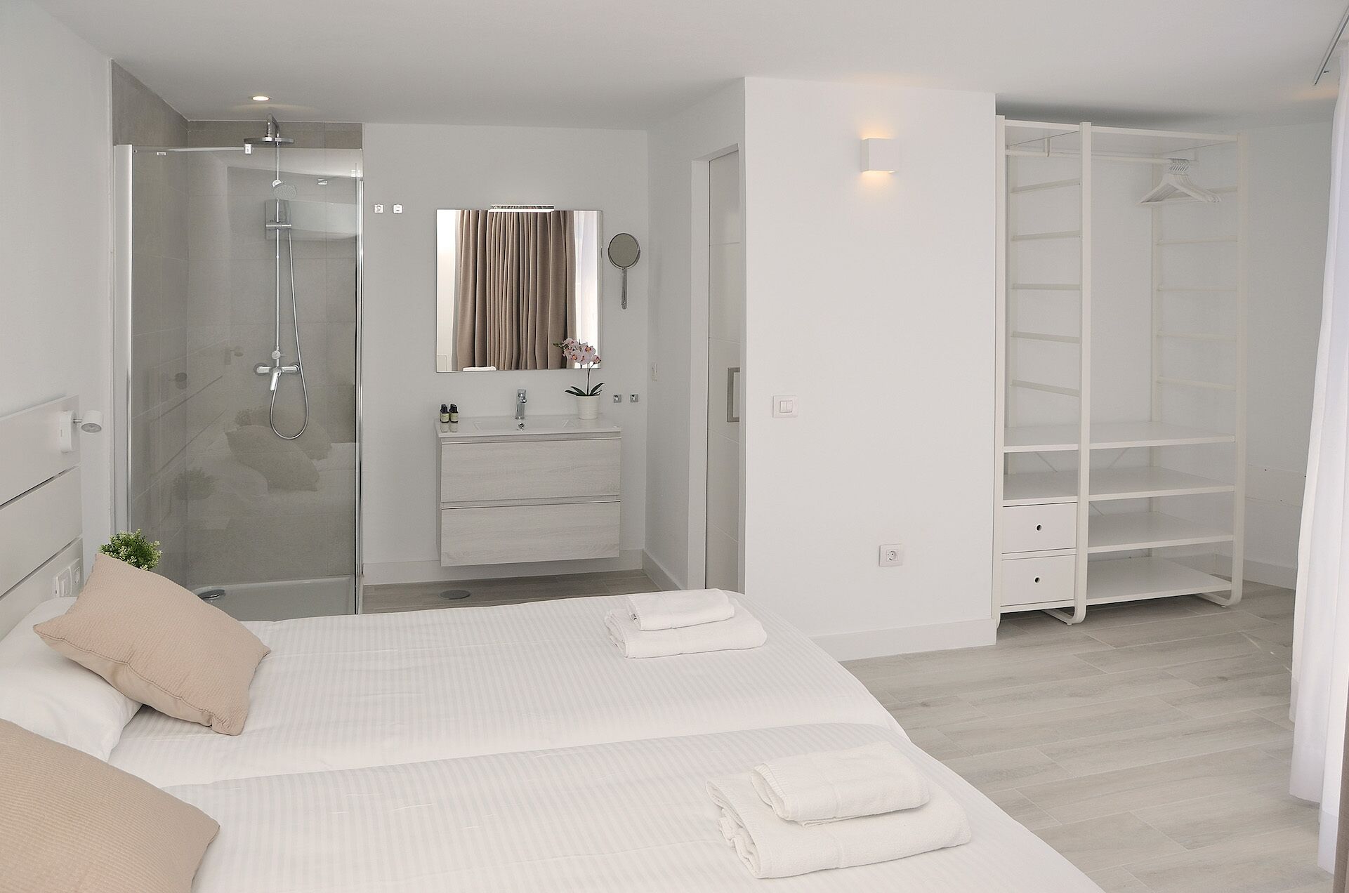 Een moderne slaapkamer met een groot bed, een inloopkast en een douche.