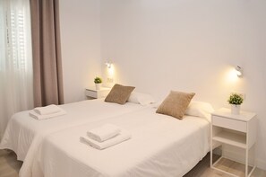 Une chambre d’hôtel avec un grand lit, deux tables de chevet équipées de lampes et une petite plante sur chaque table.