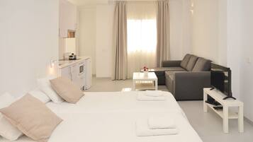 Una habitación de hotel moderna con cama, sofá, televisión y kitchenette.
