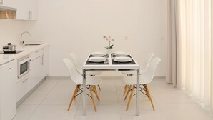 Una cocina moderna con armarios blancos, microondas integrado y un lavamanos.