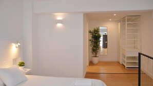 Un dormitorio con cama, mesita de noche y una planta en maceta.