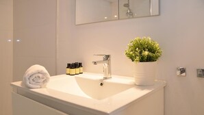 Un baño con un lavamanos blanco, un espejo y una planta en maceta.