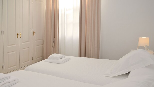 Ein Hotelzimmer mit zwei Betten, einem Kleiderschrank und einer Nachttischlampe.