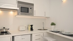 Eine kleine Küchenzeile mit Mikrowelle, Toaster, Spüle und einem kleinen Kühlschrank.