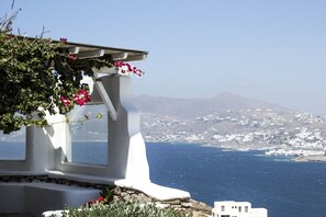 A white building with a view of the sea and a mountain in the background.