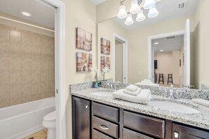 A modern bathroom with a large sink, dark cabinets, and a bathtub.