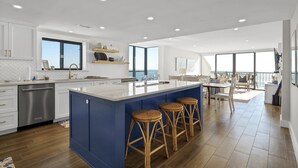 Una cocina moderna con una isla grande, taburetes de bar y vista al océano.