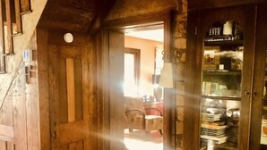 Un interior de madera con una escalera, una puerta que da a otra habitación y una estantería llena de libros.