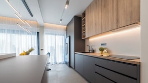 A modern kitchen with a central island, wooden cabinets, and a built-in oven. - Villa Aria (Novalja)