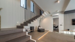 A modern interior with a staircase, seating area, and a kitchen visible in the background. - Villa Aria (Novalja)