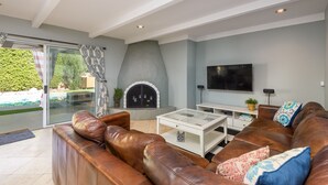 A living room with a fireplace, a TV, a sofa, and a glass door leading to a pool.