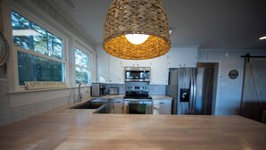A modern kitchen with a large island, stainless steel appliances, and a hanging light fixture. - Sunsets and Ramp and Dock Access on Lake Wateree (Camden)