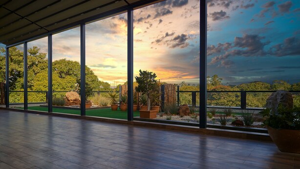 A spacious room with large windows offering a view of a landscaped garden and trees. - The Quorum (Lusaka)