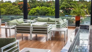 A modern outdoor seating area with white furniture and a view of lush greenery. - The Quorum (Lusaka)