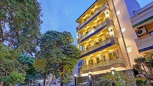 A multi-story hotel with balconies, a gated entrance, and surrounding greenery.