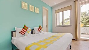 A hotel room with a large bed, a window with a view, and a door.