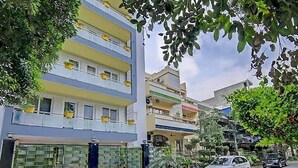 A multi-story residential building with balconies, a gated entrance, and a parked car on the street.