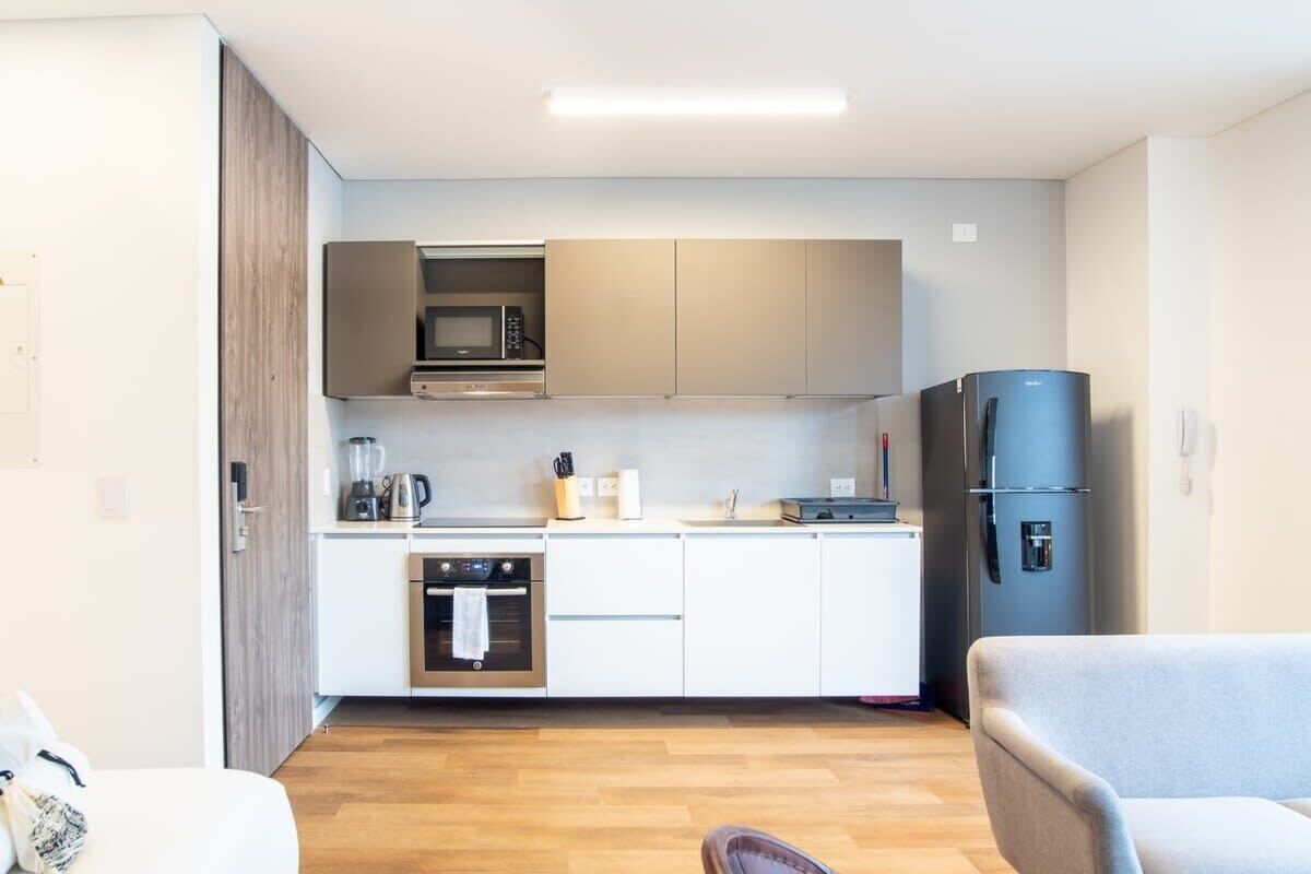 A compact kitchen with white cabinets, a microwave, a stove, and a refrigerator.