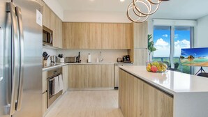 Une cuisine moderne avec des meubles en bois, des appareils électroménagers en acier inoxydable et un grand îlot central agrémenté de fruits.
