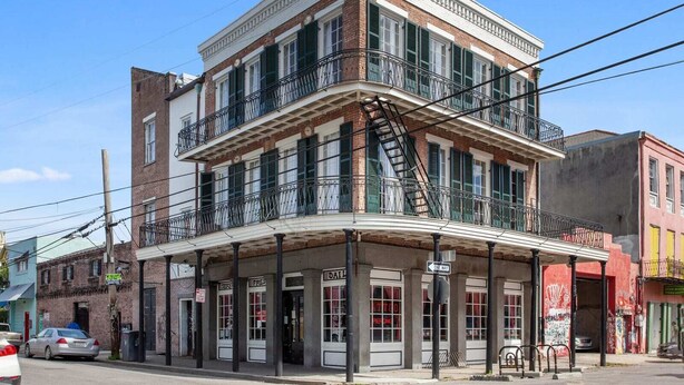 A two-story building with a balcony on the second floor, a fire escape, and a 'ONE WAY' sign. - Contemporary Marigny Apt on Frenchmen St. (New Orleans)