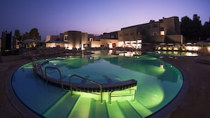 A swimming pool with a curved design, surrounded by lounge chairs and umbrellas, and adjacent to a building with multiple balconies. - Futura Club Spiagge Bianche (Syracuse)