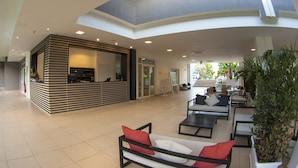 A spacious lobby with a reception desk, seating area, and a skylight. - Futura Club Spiagge Bianche (Syracuse)