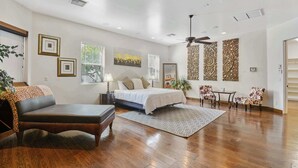 A spacious bedroom with a large bed, a sitting area with a sofa and armchair, and a dining area with a table and chairs. - Luxury 7BR Golf Mansion: Pool, Spa, Tennis Court (Scottsdale)