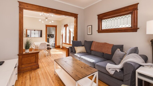 A modern living room with a sofa, coffee table, and a dining area with chairs and a table.