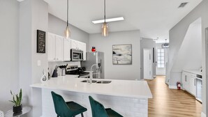 Una cocina moderna con armarios blancos, una isla grande con taburetes y luces colgantes.