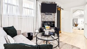 A modern living room with a fireplace, a round glass coffee table, and a sofa.