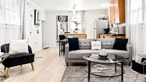 A modern living room with a sofa, coffee table, and a dining area in the background.