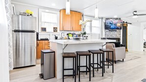A modern kitchen with a central island, stainless steel appliances, wooden cabinets, and bar stools.
