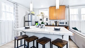 A modern kitchen with a central island, wooden cabinets, and bar stools.