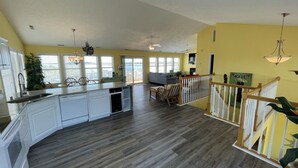 Una cocina amplia con una isla grande, armarios blancos y vistas al exterior.