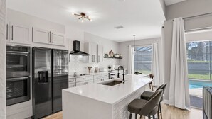 Una cocina moderna con electrodomésticos de acero inoxidable, una isla central y vistas al jardín trasero.