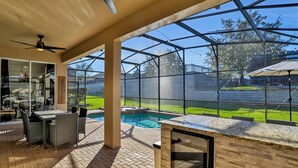 Un patio al aire libre con piscina, una parrilla y una mesa de comedor con sillas.