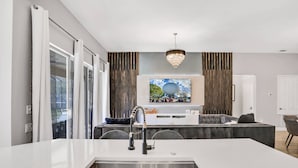 Una cocina moderna con una isla central, un lavamanos empotrado y un televisor de pantalla plana grande montado sobre la isla.