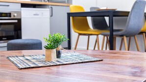 Una mesa de madera con un posavasos tejido y una pequeña planta en maceta.