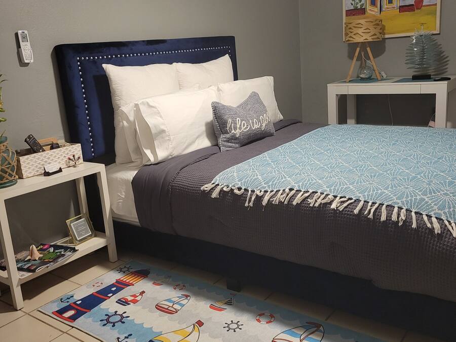 Um quarto com cama, mesas de cabeceira, um quadro e um tapete decorativo.