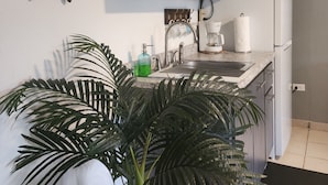 A kitchen with dark wooden cabinets, a white refrigerator, a coffee maker, and a potted plant. - Playa Escondida (Fajardo)