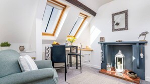 Un salon chaleureux avec un canapé, une table à manger et des chaises, une cheminée et une lucarne.