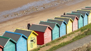 Une plage avec des cabanes de plage aux couleurs vives et une jetée en arrière-plan.