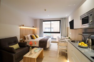 Ein modernes Hotelzimmer mit Bett, einer Couch, einem Essbereich und einer Küche.