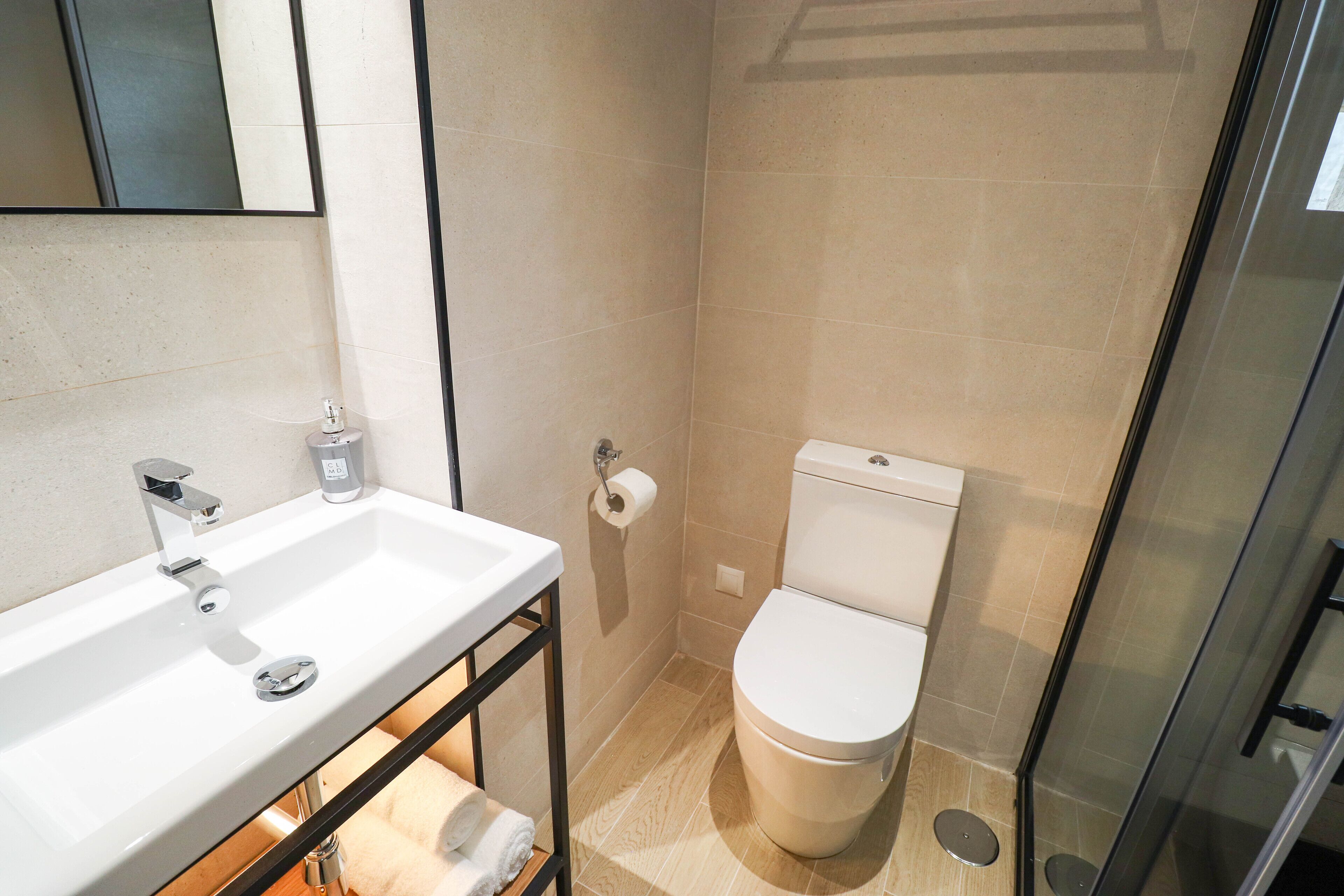 Uma casa de banho moderna com lavatório branco, sanita e cabine de duche em vidro.