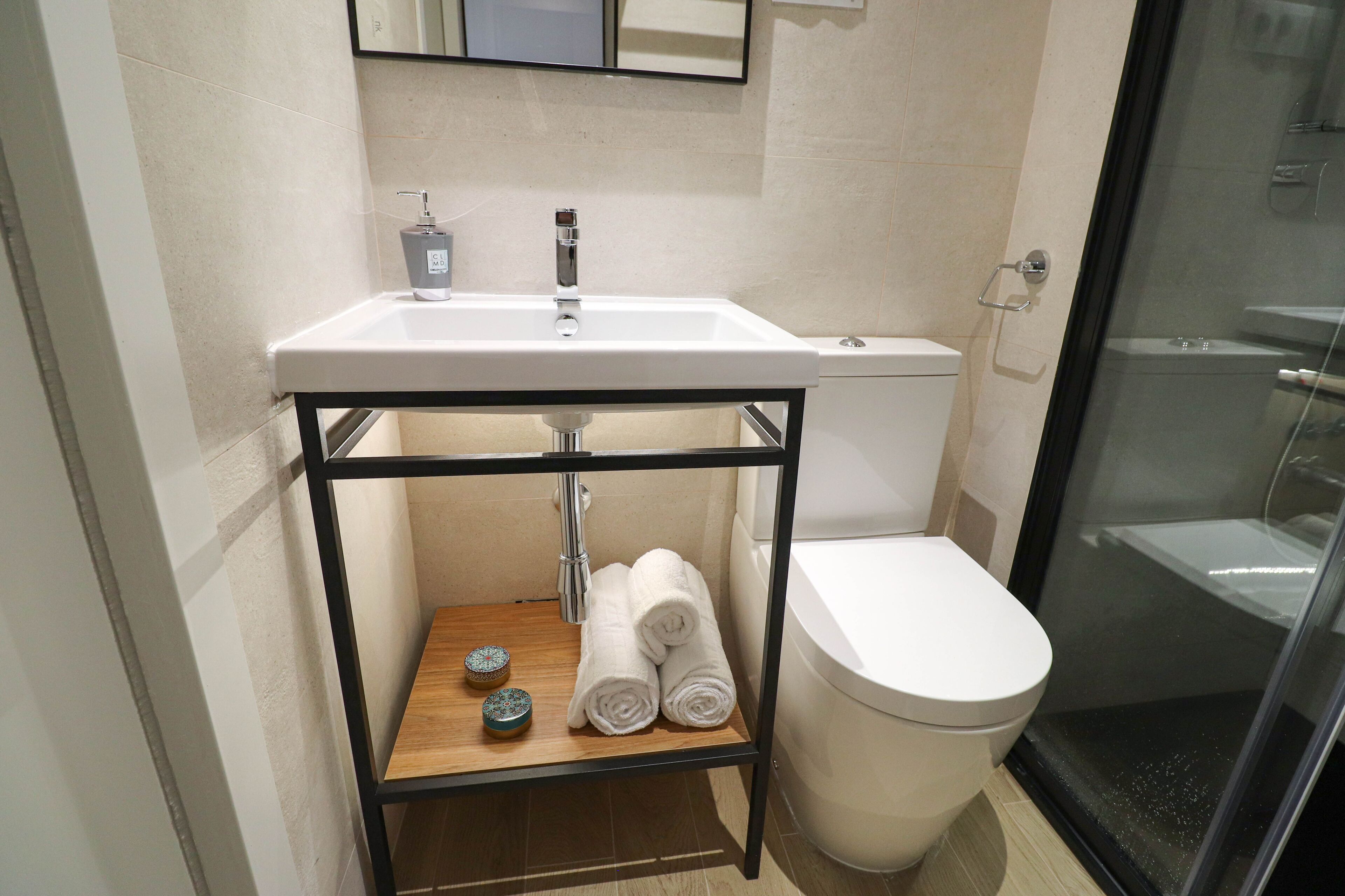 Une salle de bain moderne avec un lavabo blanc, des toilettes et une douche à parois de verre.